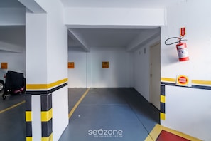 A hallway with numbered doors, a fire extinguisher, and a sign indicating a smoking area.