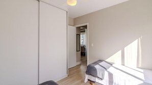 A bedroom with two beds, a ceiling fan, and a view of the hallway.