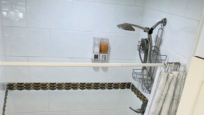 A shower with a curved design, a towel rack, and a showerhead.