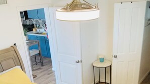 A bedroom with a bed, a white door, a small round table, and a ceiling light fixture.