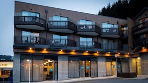 Ein mehrstöckiges Hotel mit Balkonen, großen Fenstern und einem gut beleuchteten Eingangsbereich.