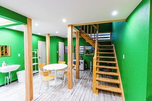 Un interno moderno con pareti verdi, una scala in legno, un lavandino bianco e un tavolo rotondo con sedie.