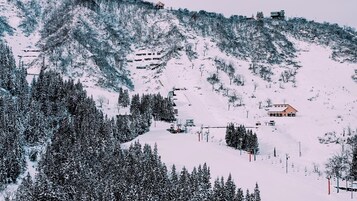 Una montagna innevata con una seggiovia e un rifugio.