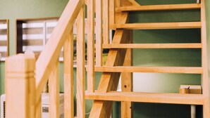 A wooden staircase with a handrail, leading to a room with green walls and a window. - 3BD Yuzawa Onsen Lodge House A (Minamiuonuma)