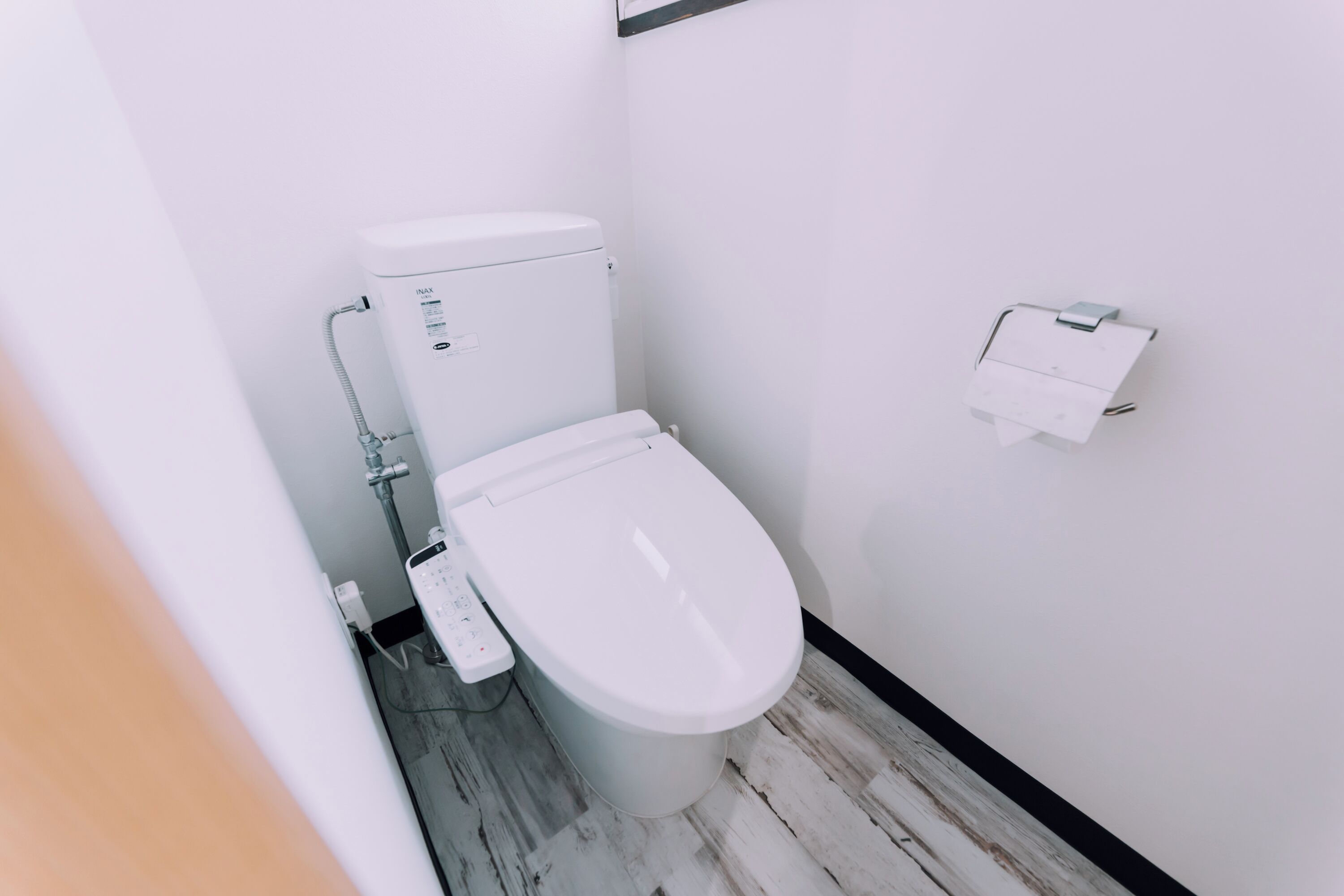 A modern bathroom with a white toilet, a bidet, and a toilet paper holder on the wall.