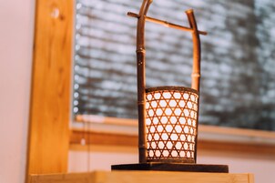 Lampada in bambù con decoro a griglia su un supporto in legno.