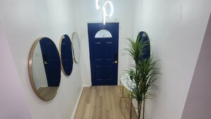 A hallway with a wooden floor, a blue door, and three wall-mounted mirrors.