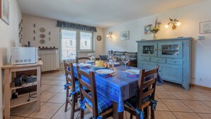 A dining area with a table set for four, a kitchen area with a blue cabinet, and a white radiator.
