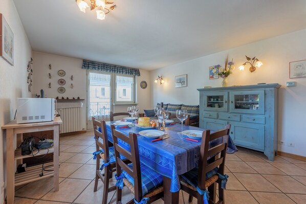 A dining area with a table set for four, a kitchen area with a blue cabinet, and a white radiator.