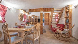 Un comedor acogedor con una mesa y sillas de madera, un sofá rojo y una estantería de madera.