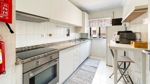 Une cuisine moderne avec des armoires blanches, des comptoirs en granit, une hotte de cuisinière en acier inoxydable et un four encastré.
