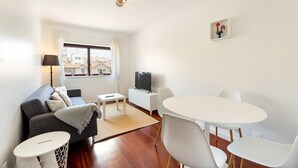 Un salon moderne comprenant un canapé, un téléviseur, une table à manger et des chaises.