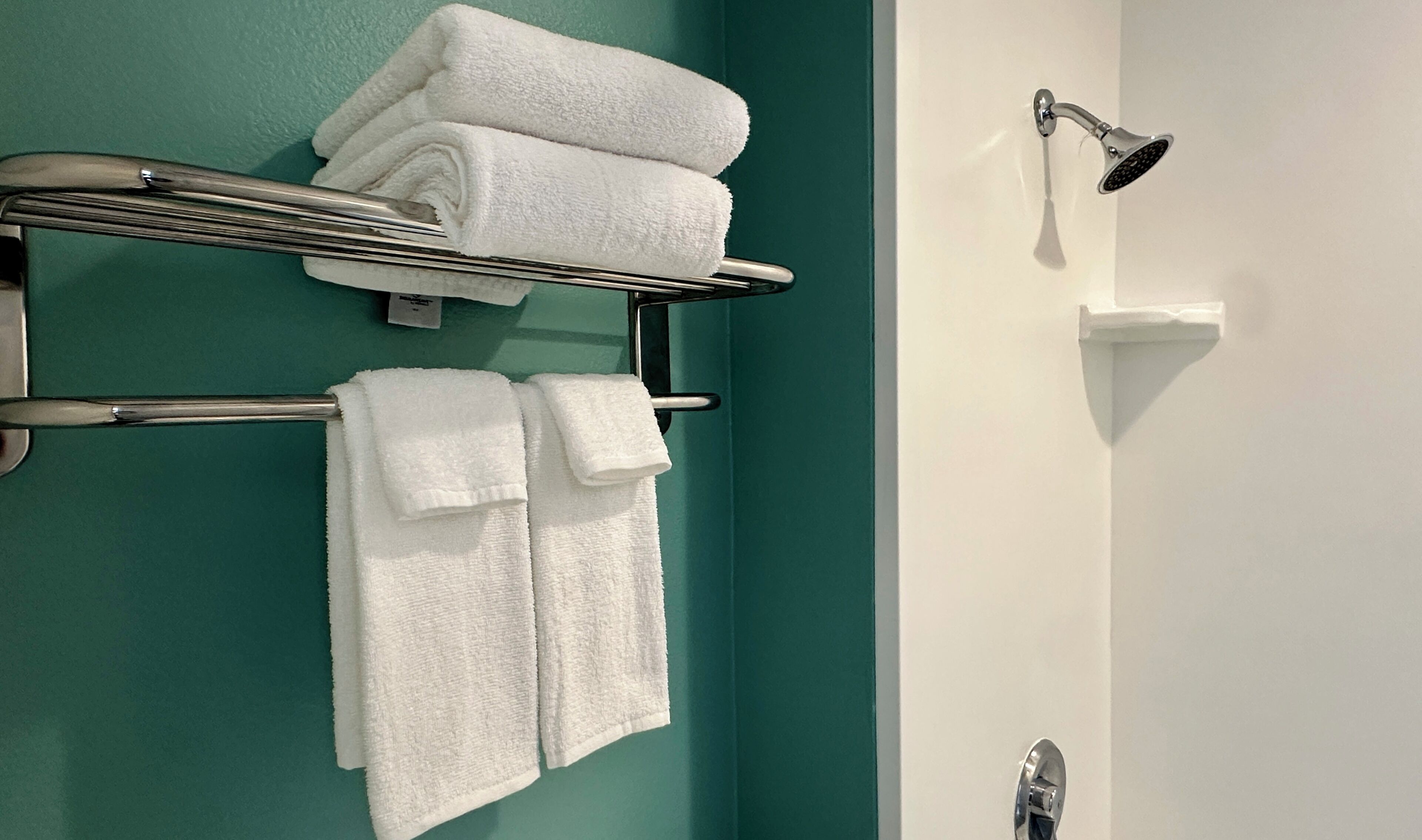 A bathroom with teal walls, a white sink, and a shower with a handheld showerhead.