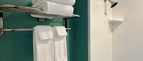 A bathroom with teal walls, a white sink, and a shower with a handheld showerhead.