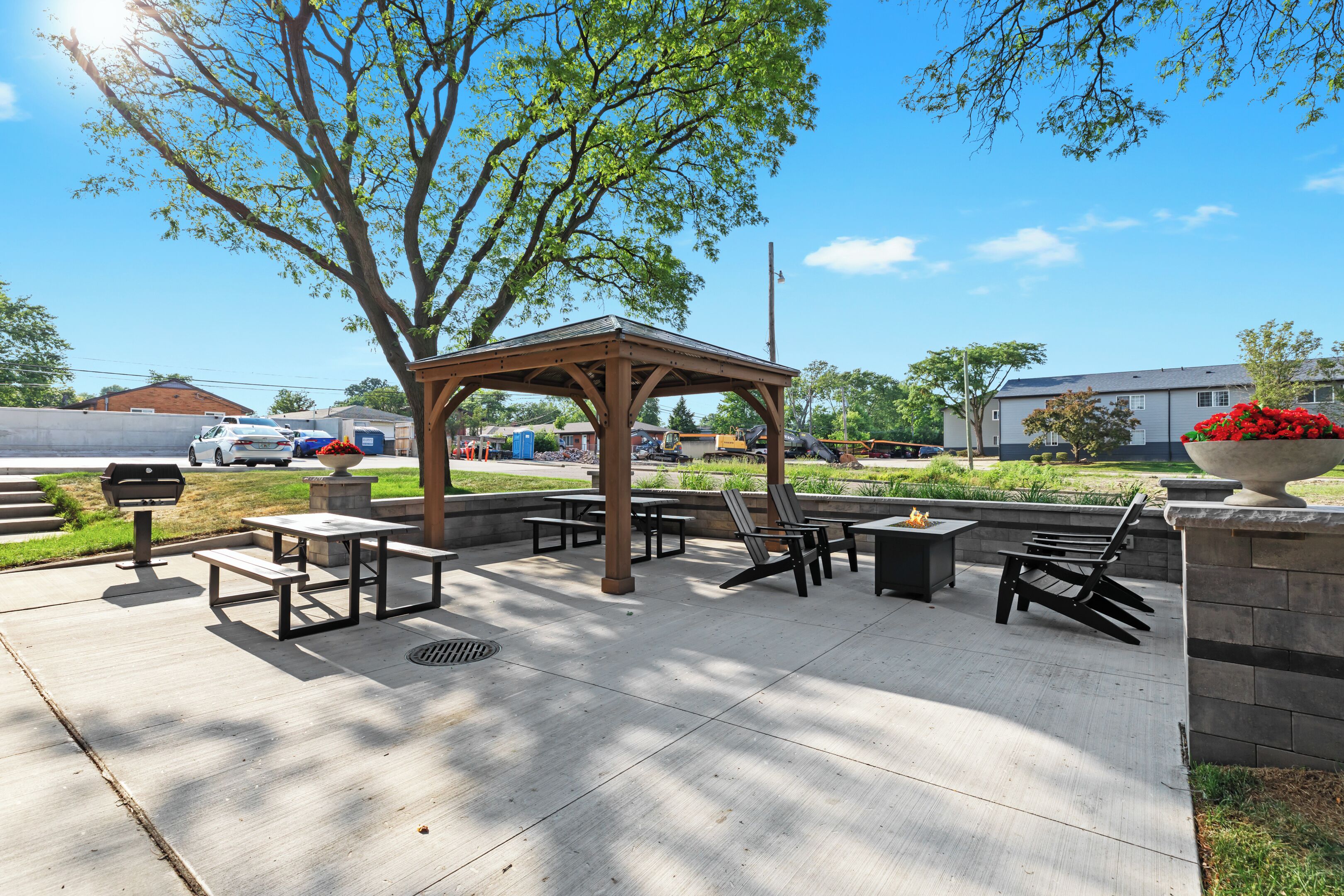 An outdoor patio with a wooden gazebo, picnic tables, and benches.