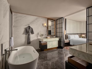 A modern bathroom with a freestanding bathtub, a vanity with a marble countertop, a large mirror, and a bed with white linens. - Intercontinental Changchun High Tech Zone (Changchun)