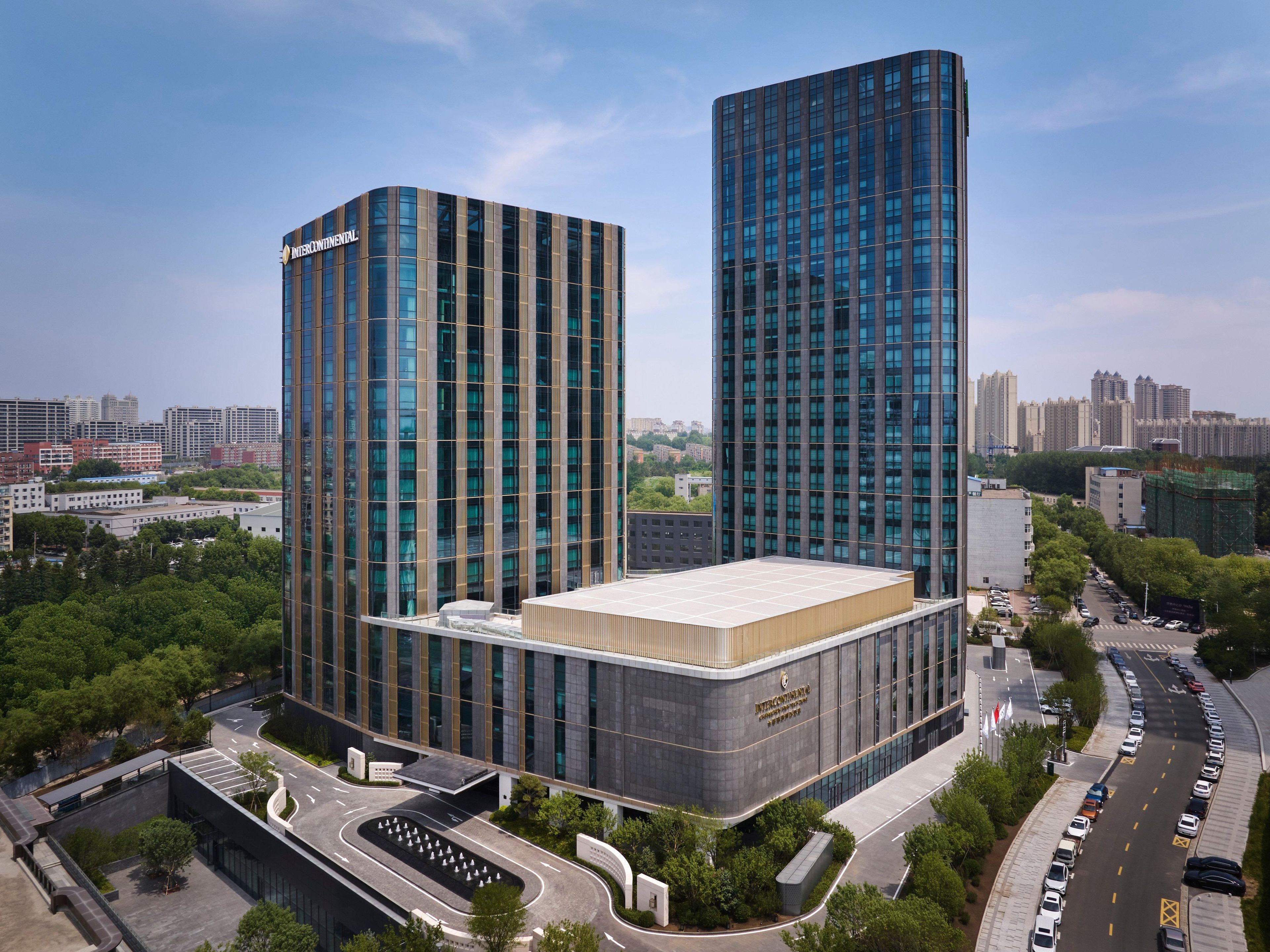 Un edificio moderno con dos torres destacadas y una estructura de techo plano en primer plano.