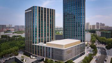 Un edificio moderno con dos torres destacadas y una estructura de techo plano en primer plano.