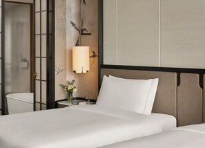 Hotelkamer met een bed, nachtkastje met een lamp, vaas met bloemen en een muur met een muurschildering van een vogel.