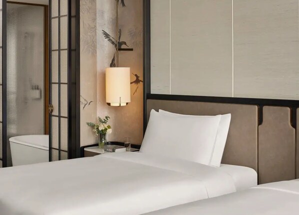 A hotel room with a bed, a nightstand with a lamp, a vase with flowers, and a wall with a bird mural. - Intercontinental Changchun High Tech Zone (Changchun)