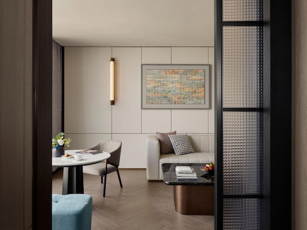 A modern living room with a sofa, a round table with a chair, a coffee table, and a wall-mounted artwork. - Intercontinental Changchun High Tech Zone (Changchun)