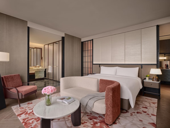 A hotel room with a bed, two armchairs, a small table with a vase of flowers, a nightstand with a lamp, and a large mirror on the wall. - Intercontinental Changchun High Tech Zone (Changchun)