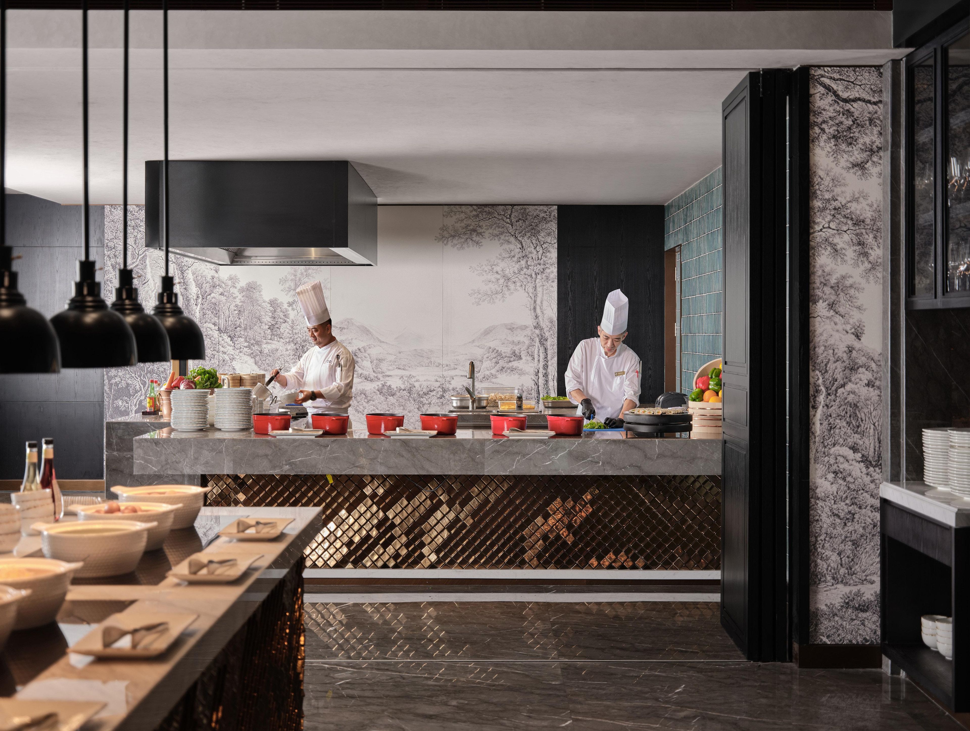 A modern kitchen with chefs preparing food, marble countertops, and a wine rack.