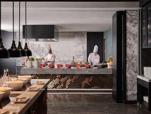 Een moderne keuken met koks die gerechten bereiden, marmeren aanrechtbladen en een wijnrek.