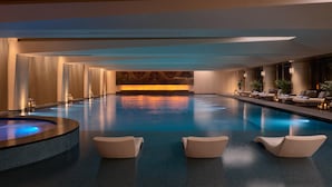A spacious indoor swimming pool with a hot tub, lounge chairs, and a marble wall in the background. - Intercontinental Changchun High Tech Zone (Changchun)