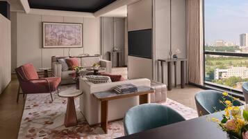 Una sala de estar moderna con un sofá, sillones, una mesa de centro y un televisor montado en la pared.