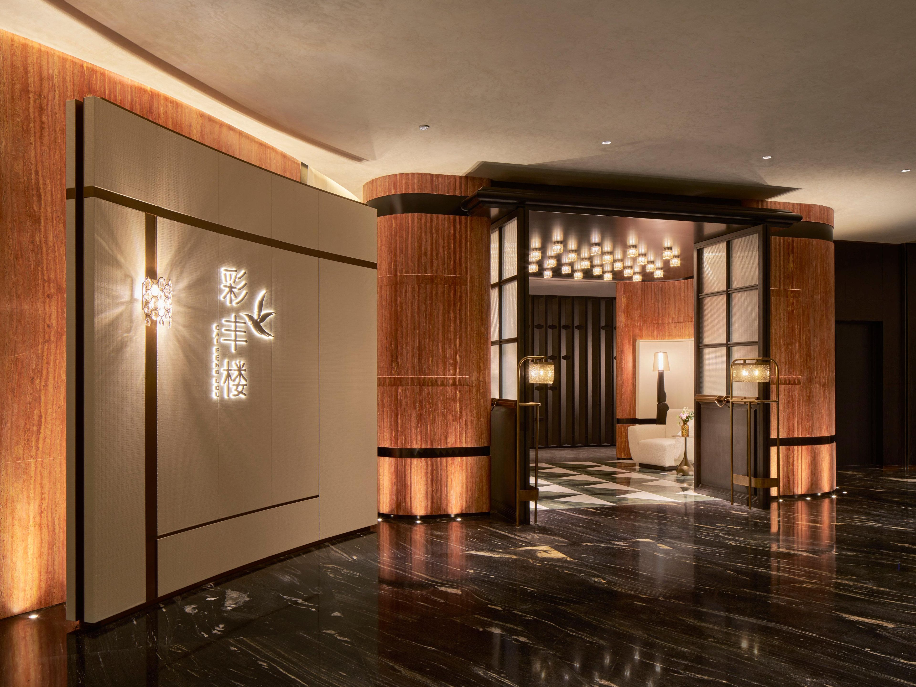 A modern hotel lobby with a polished marble floor, wooden accents, and a traditional Asian-style entrance with illuminated signage.