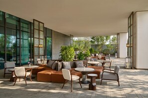 Een ruim buitenterrein met moderne meubels, grote ramen en veel groen.