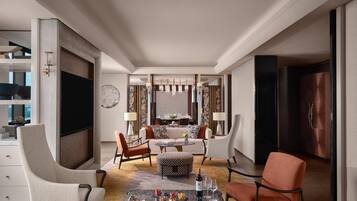 Una habitación de hotel moderna con comedor, un televisor de pantalla plana grande y vistas a la ciudad.