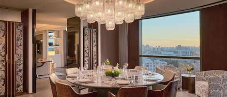 A modern dining area with a round table, multiple chairs, and a chandelier.