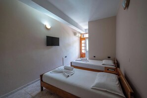 A hotel room with two single beds, a flat-screen TV mounted on the wall, and a window with a view. - Hotel Nika Radhime (Vlorë)