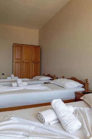 A hotel room with two beds, wooden headboards, and a large wardrobe. - Hotel Nika Radhime (Vlorë)