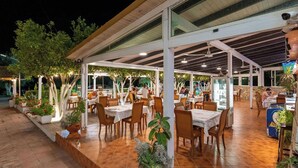 An outdoor dining area with tables and chairs, surrounded by potted plants and trees. - Hotel Nika Radhime (Vlorë)