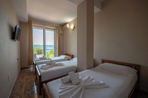 A hotel room with two beds, a TV, and a balcony with a view. - Hotel Nika Radhime (Vlorë)
