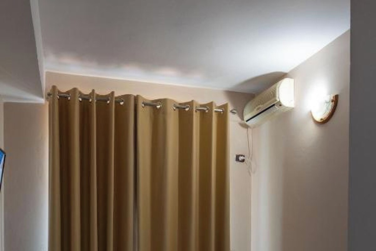 Ein Hotelzimmer mit zwei Betten, einem Badezimmer mit Duschvorhang und einer Klimaanlage an der Wand.