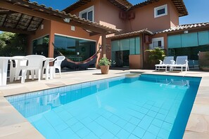 A swimming pool with white lounge chairs and a hammock.