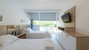 Quarto de hotel com duas camas, televisão, varanda com vista para o verde e design moderno.