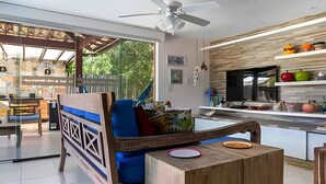 Uma cozinha moderna com ilha de madeira, área de jantar com uma cadeira azul e vista para a cidade através de grandes janelas.