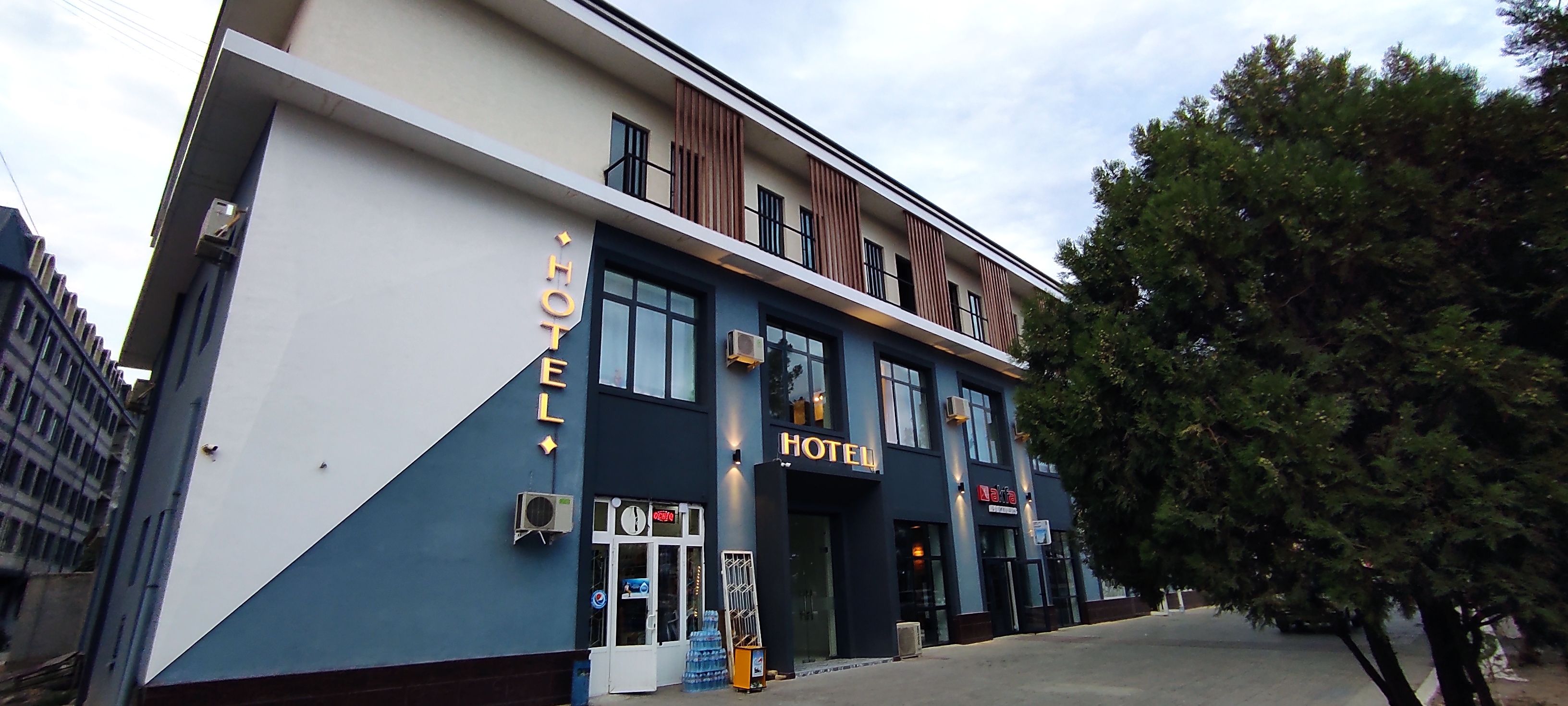 A hotel with a modern facade, large windows, and a sign indicating it is open.