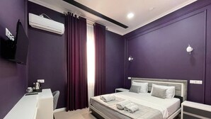 A modern hotel room with a bed, a desk, and an air conditioning unit. - Emin Hotel (Margilan)