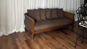 A living room with a brown sofa, white curtains, a wooden floor, and a black metal chair. - Cool 1- bedroom studio with AC in Spring Lake (Spring Lake)