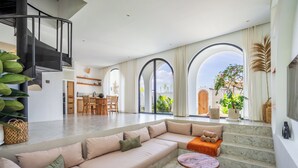 A spacious living area with a modern staircase, a dining area, and large windows offering views of the outdoors. - Unu Villa by Betterplace (Canggu)