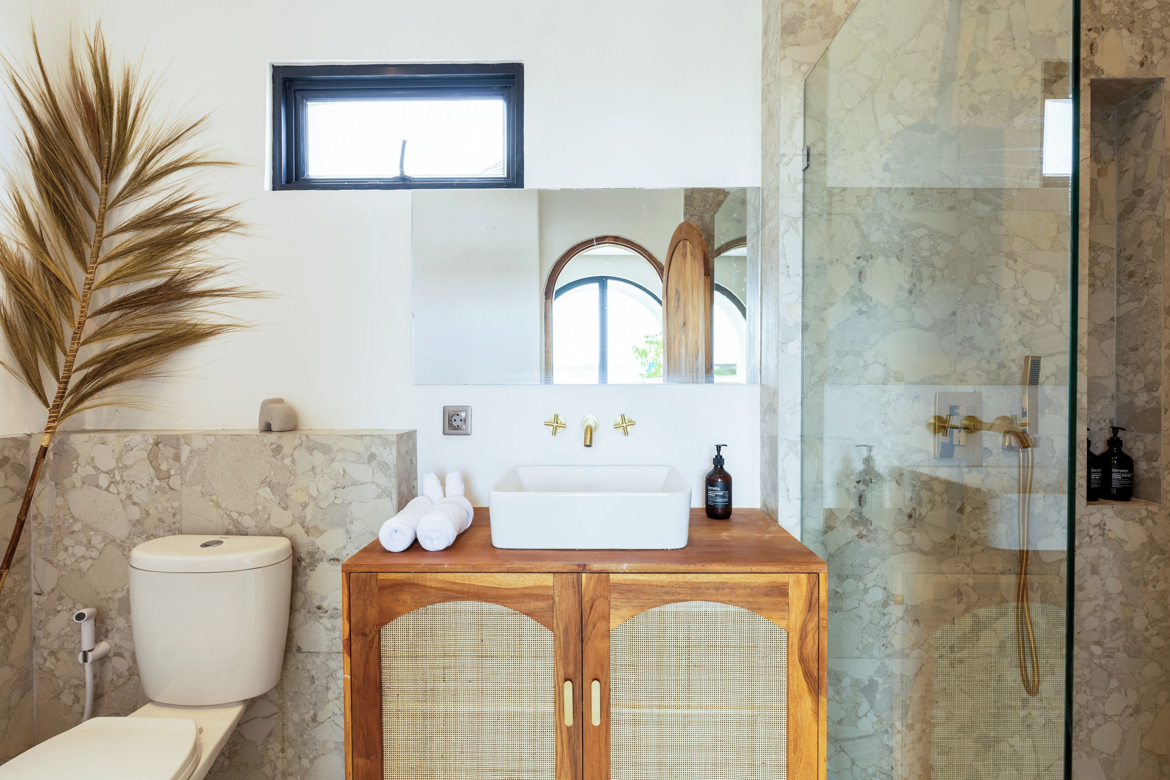 A bathroom with a white sink, wooden cabinet, and a glass shower enclosure.