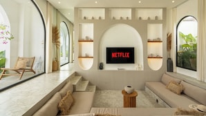 A modern living room with a large TV mounted on a wall, a sofa, and a coffee table. - Unu Villa by Betterplace (Canggu)