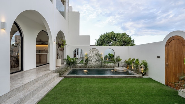 A modern house with a swimming pool, white walls, and arched doorways. - Unu Villa by Betterplace (Canggu)