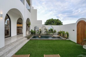 Une maison moderne dotée d’une piscine, de murs blancs et de portes en arc de cercle.